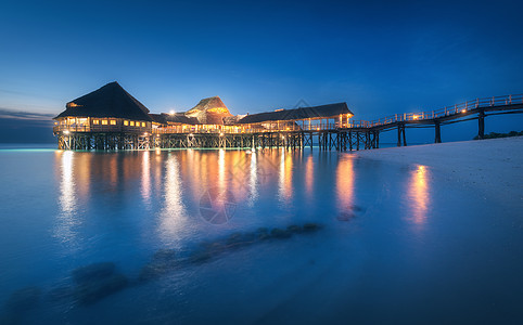 夏天晚上水上美丽的木制餐厅风景与酒店海上,照明,码头,沙滩,蓝天灯光反射模糊的水黄昏桑给巴尔,非洲图片
