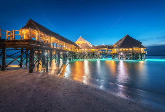 夏天晚上水上美丽的木制餐厅风景与酒店海上,照明,码头,沙滩,蓝天灯光反射模糊的水黄昏桑给巴尔,非洲图片