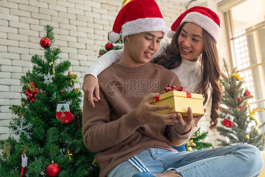 美丽的亚洲女孩圣诞节节日问候时给她的男朋友个惊喜的圣诞礼物图片