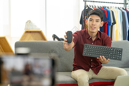 轻的亚洲男线商家博主用智能手机录制场景Vlog视频,以查看IT产品线Influencer关于社交媒体图片