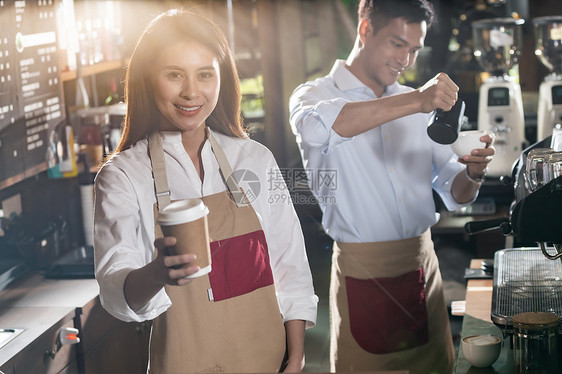 亚洲咖啡师的肖像,走咖啡杯,并咖啡馆为客户服务,其他咖啡师后台工作图片