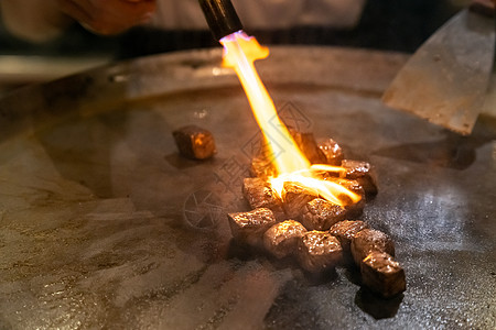 烤牛肉铁板烧食谱日本烤牛肉烹饪锅与刮刀煤气燃烧器火焰背景图片