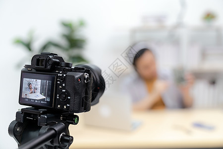轻的亚洲男ITVlogger博主场景直播关于技术升级笔记本电脑硬盘上用数码相机录制场景Vlog视频线Influe背景图片