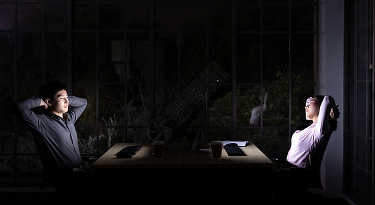 轻的亚洲成商人妇女深夜工作时,办公室里用台式电脑笔记本电脑伸展身体用努力工作工作图片