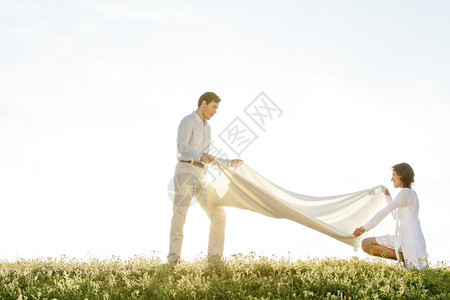 在阳光明媚的白天在草地上撒野餐毯子图片
