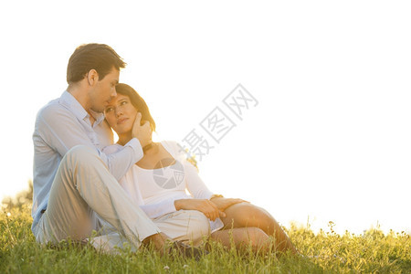 浪漫的年轻情侣坐在草地上与晴空对准天图片