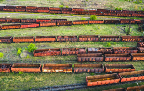 火车的空中景象铁路上老旧的生锈马车顶部景象重工业风景夏季日落时有火车绿树和草地火车站图片
