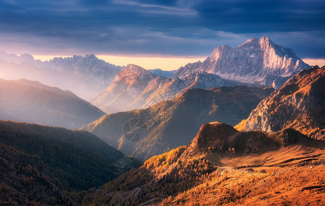 秋天落日时美丽的山峰秋天时日落的多洛米山意大利风景与岩石日光束森林山丘橙色草和树木多彩的天空风景与秋天的雾中山谷风景图片