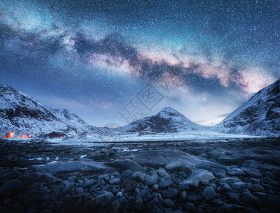 冰雪上方的覆盖了冬季的山峰和石滩冬季晚上在洛夫顿岛诺威北极风景有蓝星空海边雪岩银河系美丽的空间和自然图片