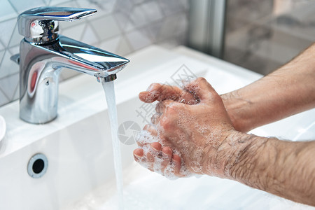 男子在家中浴室洗手池用肥皂和热水洗手男子正在清洁手预防冠状腺爆发的卫生图片
