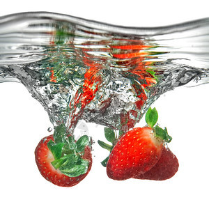 新鲜草莓滴入水中白地上隔离喷洒图片