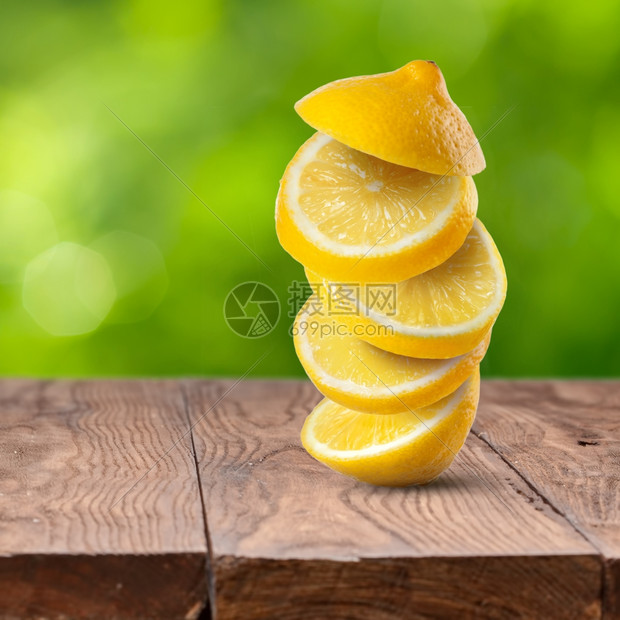 以绿色天然背景在木制桌上的新鲜柠檬切片图片