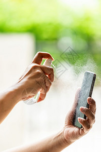 使用气瓶喷洒的阿洛科霍醇喷雾器进行近距离清洁移动电话安全消毒防止并保护不被细菌感染图片