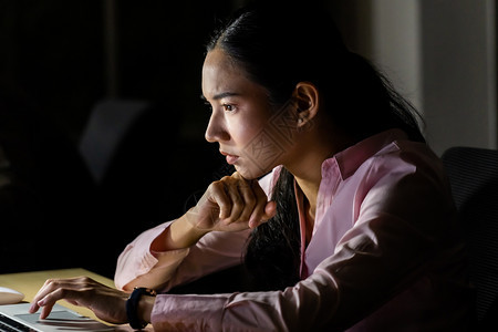 年轻的亚洲女商人辛勤工作深夜在办公室用笔记本电脑工作图片