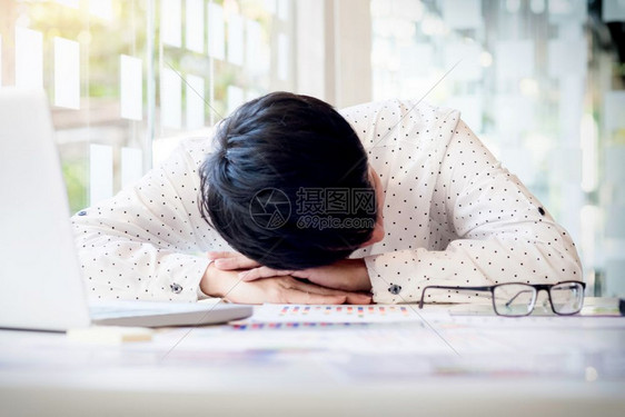 在办公室桌计算开支时疲劳的商人睡觉图片