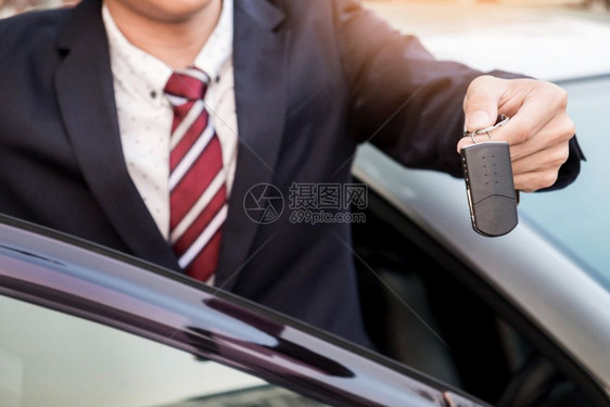 提供汽车钥匙的年轻成功商人关闭司机显示手键图片
