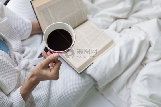 床上女人的柔软照片上面有旧书咖啡和复制空间图片
