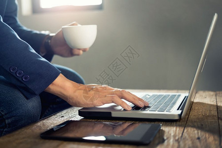 生意人喝着热咖啡忙着在笔记本电脑上工作图片素材