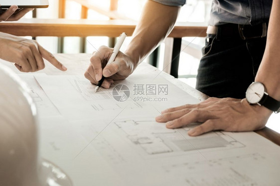 建筑工程师在桌子上讨论蓝图手贴上印刷项目图片
