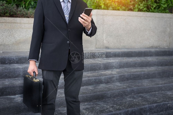 商人穿黑色西装在户外使用现代智能手机图片