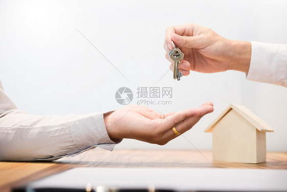 诉讼财产代理人坐在办公桌签署合同后向客户移交房屋钥匙图片