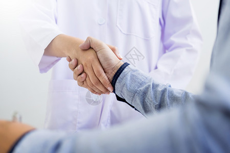 医生在务室与病人握手佩戴眼镜听诊器和化验室外套图片