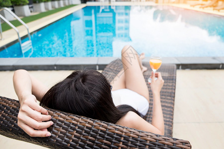 美丽的女孩喝世界鸡尾酒躺着游泳池暑假概念图片