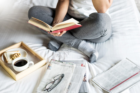 妇女早上在床上看书或报纸喝咖啡图片