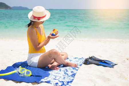 在沙滩上的年轻女孩在用防晒霜图片