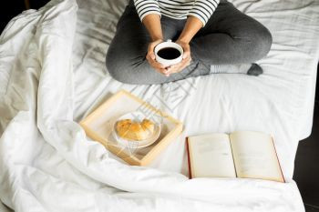 妇女早上在床上喝咖啡读书图片