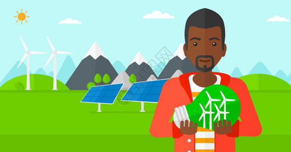 一名绿色发电厂旁手握绿色概念灯泡的非裔男子图片
