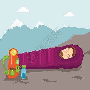 在山上露营时睡在睡袋里的人图片