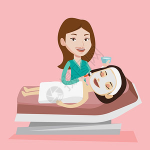 紫菜面美容师对院女客户的脸部面在美容过程中年轻女躺在美容院桌上