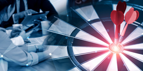 成功战略概念的商业目标红镖箭在飞板上的中枢目标在背景中工作的商界人士显示业务目标的准确和成功率图片