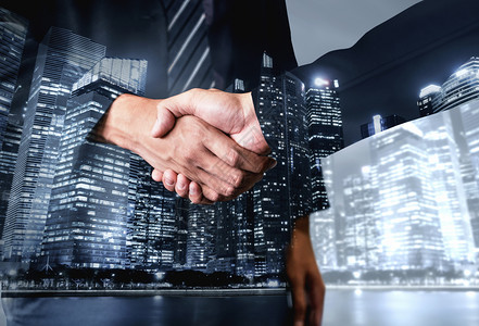 握手城市商业界人士在城市办公大楼上握手的双重背景背景