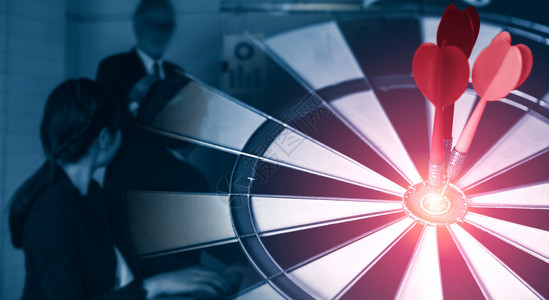成功战略概念的商业目标红镖箭在飞板上的中枢目标在背景中工作的商界人士显示业务目标的准确和成功率图片