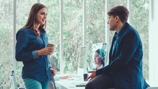男士牛仔裤在现代办公室交谈的男女背景
