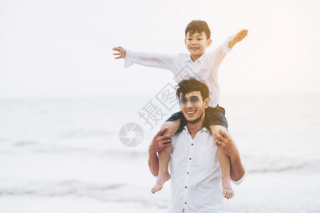 男孩张开双臂骑在父亲肩上图片