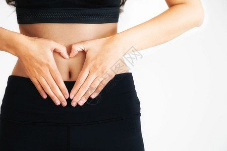 身穿运动服的年轻女在腹部做爱心形状的动作饮食体重下降和健康营养概念图片