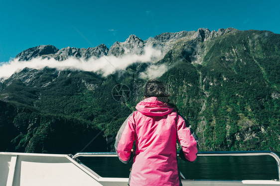 在甲板上观看新西兰南部岛屿风景的女旅行者图片