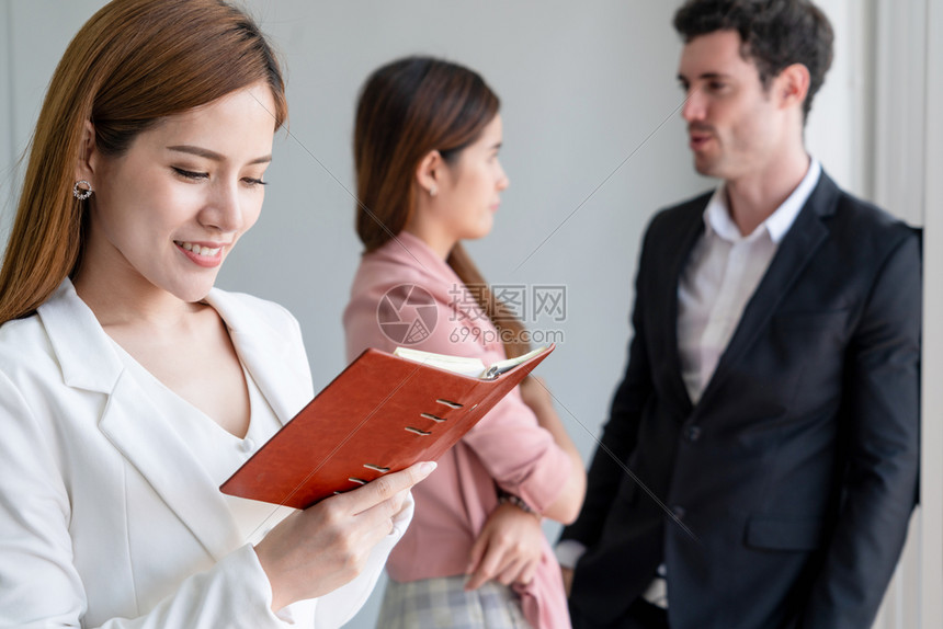 快乐的年轻女商人在办公室阅读书图片