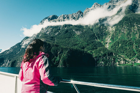 在甲板上观看新西兰南部岛屿风景的女旅行者图片