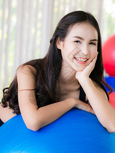 年轻女子趴在瑜伽球上图片