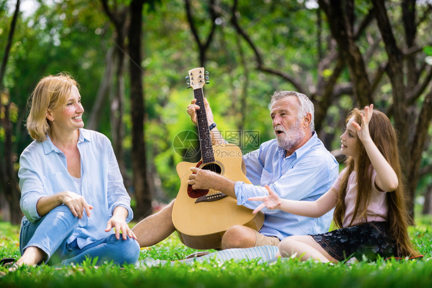 一家三口弹吉他坐在公园里一起唱歌图片