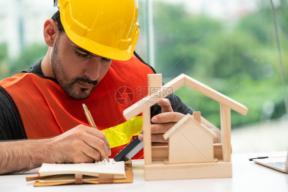 青年建筑工人或程师在办公桌与设计师在进行室内设计图片