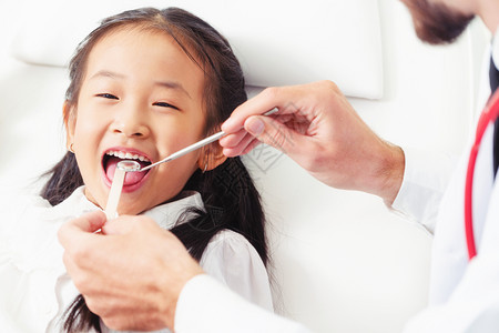 友好的年轻牙医在诊所检查儿童牙齿图片