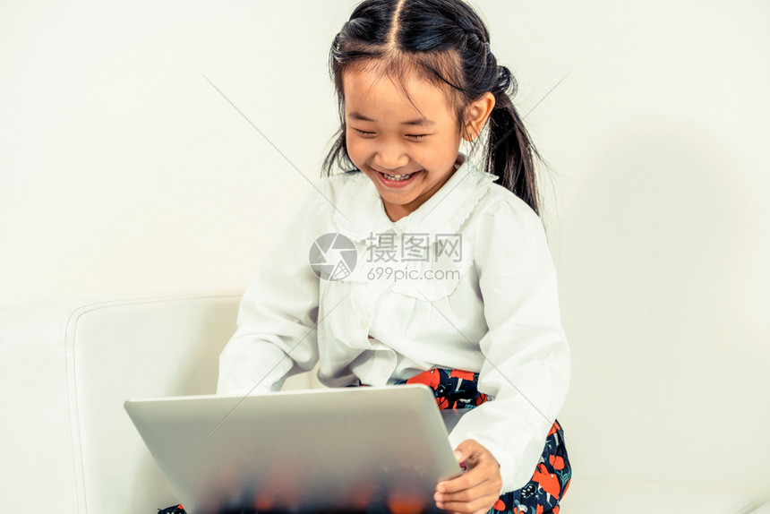 小美女坐在沙发上拿着电脑在看动画片图片
