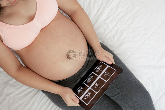 幸福的孕妇在家中躺着图片