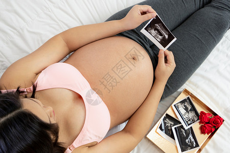 幸福的孕妇在家中躺着图片