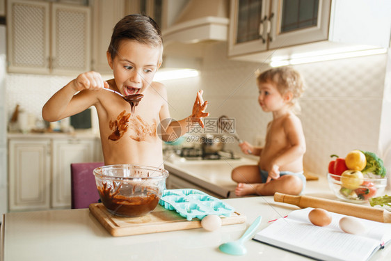 可爱男孩在碗里尝到融化巧克力准备做糕点图片